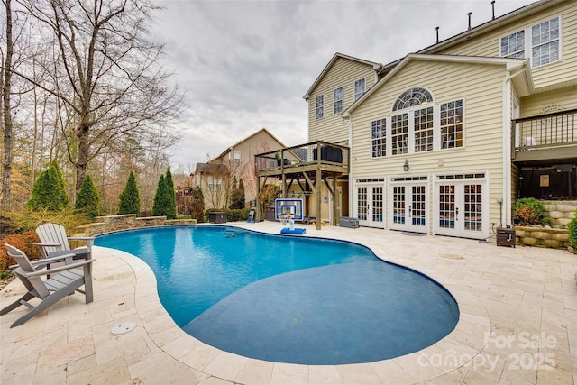 outdoor pool featuring a patio, french doors, and a wooden deck