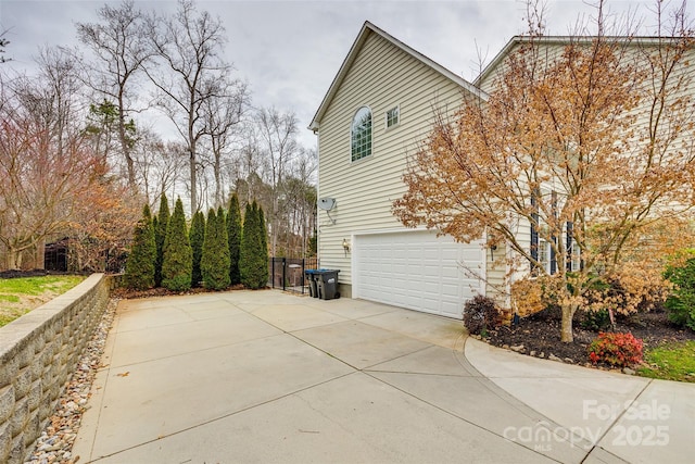 view of side of home with concrete driveway and an attached garage