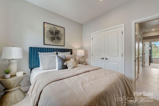 bedroom with attic access, a closet, and wood finished floors