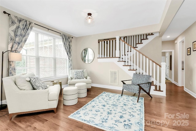 sitting room with stairway, baseboards, visible vents, and wood finished floors