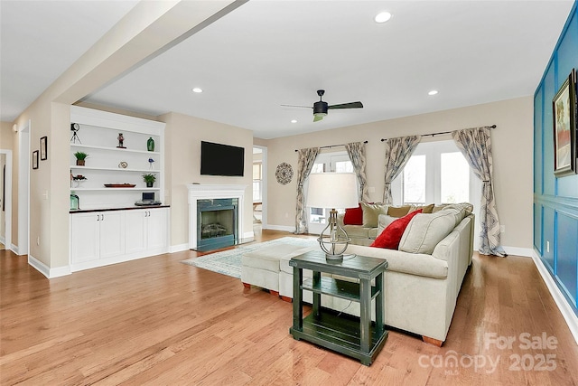 living room with a high end fireplace, recessed lighting, light wood finished floors, and ceiling fan