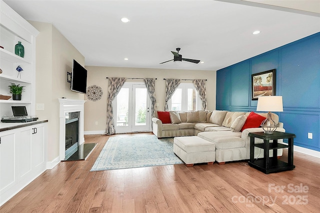 living room featuring light wood finished floors, built in features, a fireplace with flush hearth, recessed lighting, and a ceiling fan