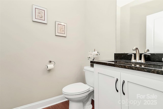 bathroom with vanity, toilet, wood finished floors, and baseboards