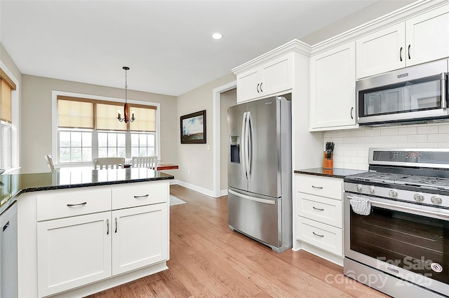 kitchen with light wood finished floors, decorative backsplash, hanging light fixtures, white cabinets, and appliances with stainless steel finishes