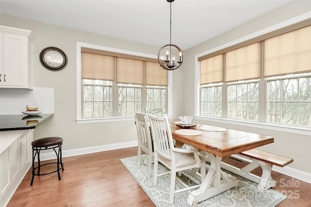 dining area featuring an inviting chandelier, baseboards, and light wood finished floors