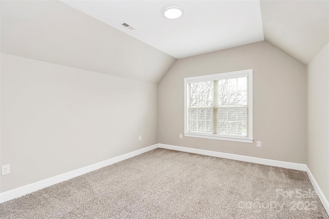 additional living space with visible vents, carpet floors, baseboards, and vaulted ceiling