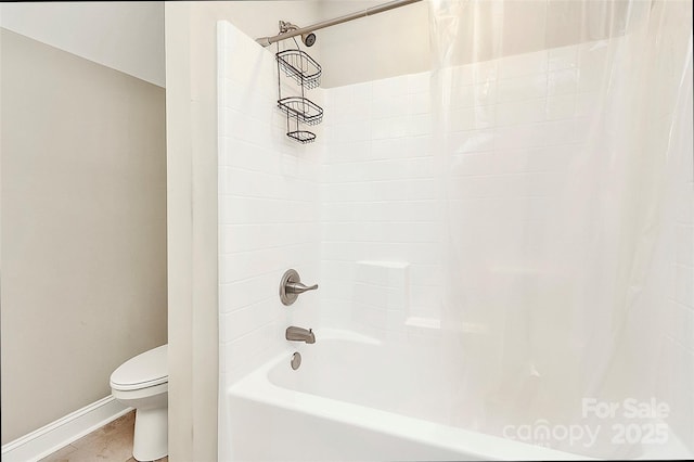 bathroom featuring baseboards, toilet, and shower / bath combination with curtain