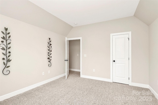 unfurnished bedroom with lofted ceiling, light colored carpet, and baseboards