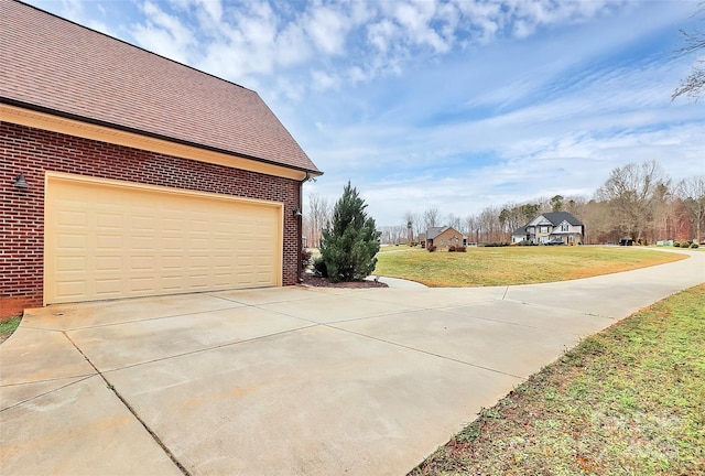 view of home's exterior with roof with shingles, concrete driveway, a garage, a lawn, and brick siding