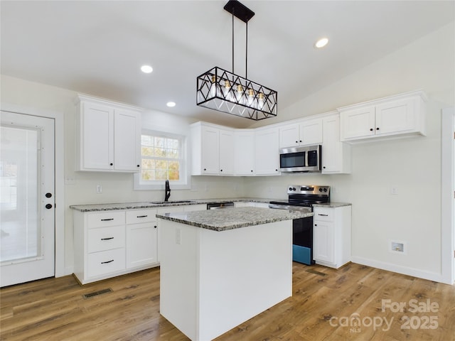 kitchen featuring visible vents, appliances with stainless steel finishes, white cabinetry, a kitchen island, and a sink