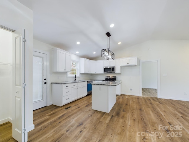 kitchen with appliances with stainless steel finishes, dark stone countertops, a center island, white cabinetry, and pendant lighting