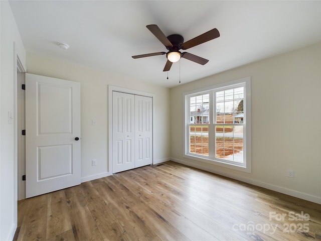 unfurnished bedroom with baseboards, a closet, and light wood-style floors