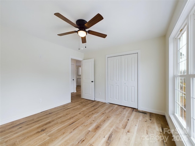 unfurnished bedroom featuring visible vents, a ceiling fan, baseboards, a closet, and light wood-type flooring