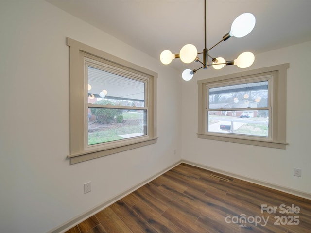 unfurnished dining area featuring baseboards, visible vents, a chandelier, and dark wood-type flooring