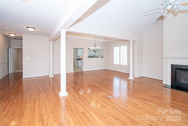 unfurnished living room featuring light wood-type flooring, a glass covered fireplace, ceiling fan, and ornate columns