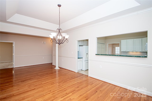 unfurnished dining area featuring a raised ceiling, crown molding, and light wood-style flooring