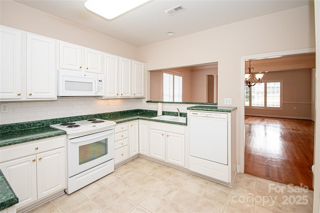 kitchen featuring dark countertops, visible vents, white cabinetry, a sink, and white appliances