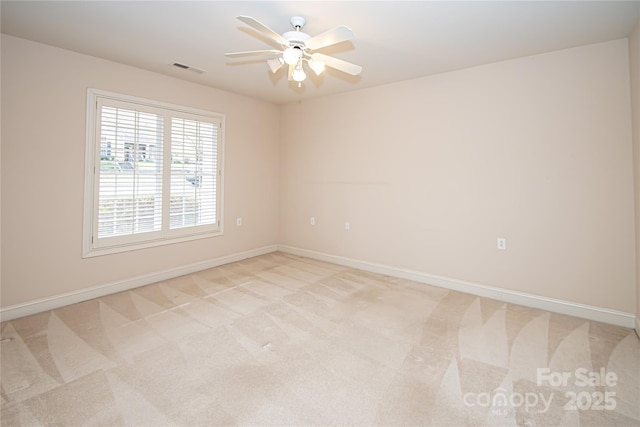 empty room featuring a ceiling fan, light carpet, visible vents, and baseboards