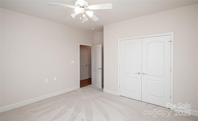 unfurnished bedroom featuring baseboards, a closet, a ceiling fan, and light colored carpet