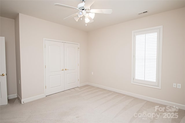 unfurnished bedroom with baseboards, visible vents, a ceiling fan, light colored carpet, and a closet