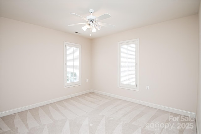 empty room with a healthy amount of sunlight, light carpet, visible vents, and baseboards