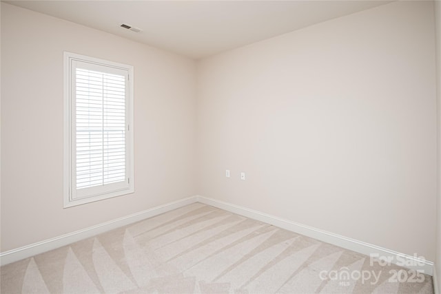 unfurnished room featuring light colored carpet, visible vents, and baseboards