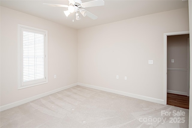 unfurnished room with baseboards, a ceiling fan, and light colored carpet