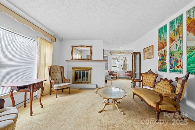 living area with a baseboard radiator, a fireplace, a textured ceiling, and light colored carpet