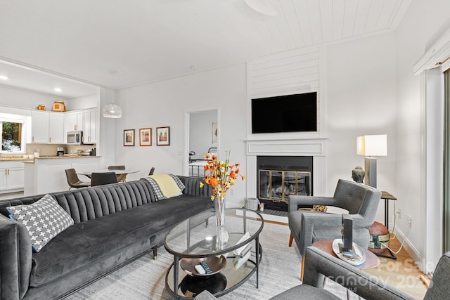 living area with light wood-type flooring, recessed lighting, baseboards, and a glass covered fireplace