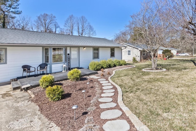 ranch-style home with a shingled roof and a front yard