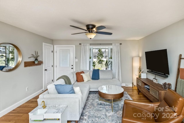 living room featuring ceiling fan, baseboards, and wood finished floors