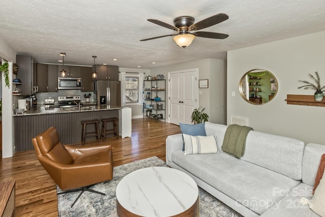 living room featuring ceiling fan, a textured ceiling, wood finished floors, and recessed lighting