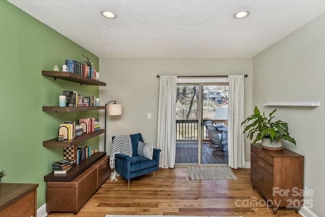 living area featuring baseboards, wood finished floors, and recessed lighting