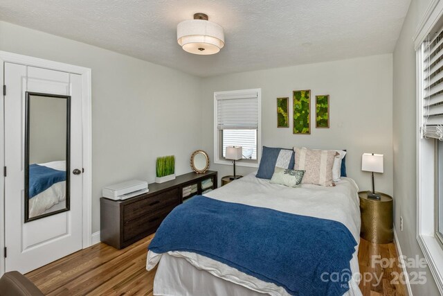 bedroom with a textured ceiling and wood finished floors