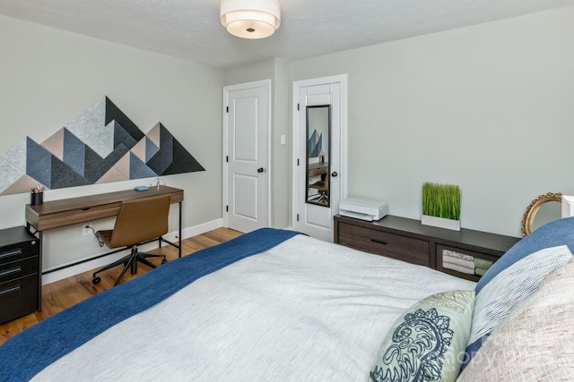 bedroom featuring dark wood-type flooring, a textured ceiling, and baseboards