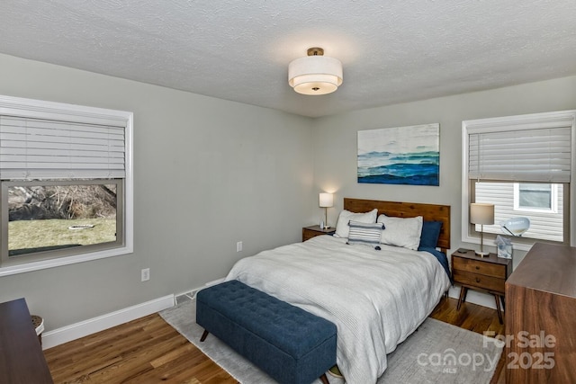 bedroom with a textured ceiling, baseboards, and wood finished floors