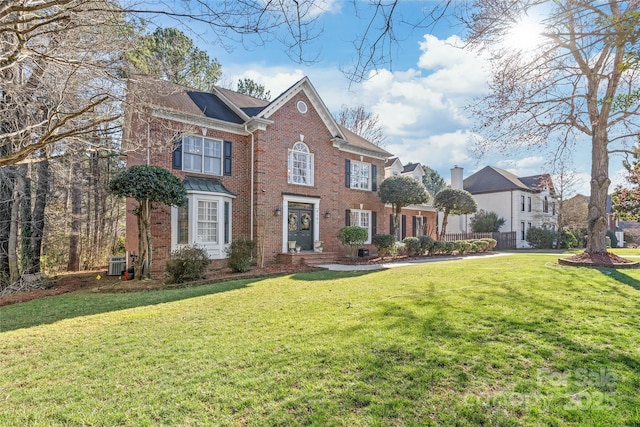 view of front facade featuring a front yard, central AC unit, and brick siding