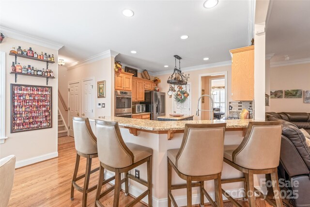 5101 Belicourt Dr, Charlotte, NC 28277 - kitchen featuring a peninsula, light wood-style floors, appliances with stainless steel finishes, decorative backsplash, and a kitchen bar