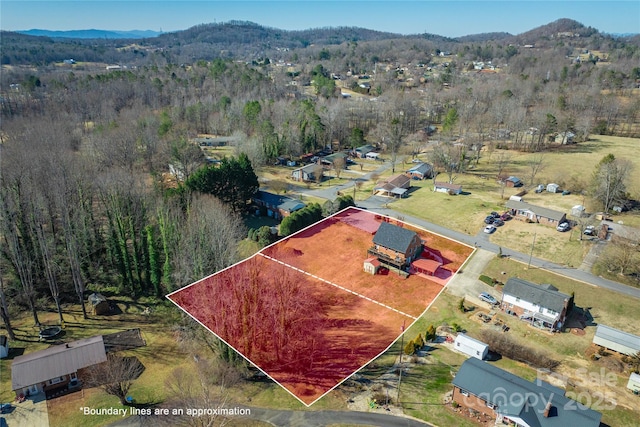 drone / aerial view featuring a wooded view and a mountain view