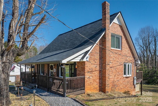 view of front of home with covered porch, brick siding, a chimney, and roof with shingles