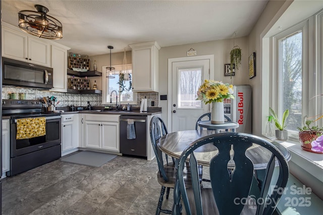 kitchen featuring dishwashing machine, black range with electric cooktop, a sink, decorative backsplash, and dark countertops