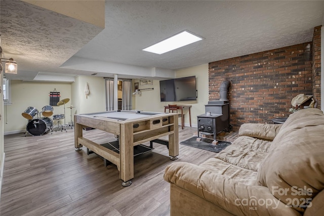 game room with a textured ceiling, wood finished floors, a wood stove, and baseboards