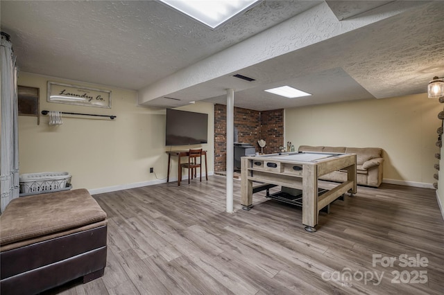 recreation room with visible vents, a textured ceiling, baseboards, and wood finished floors