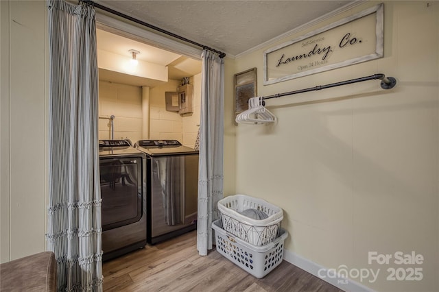 washroom with washing machine and dryer, a textured ceiling, wood finished floors, laundry area, and electric panel