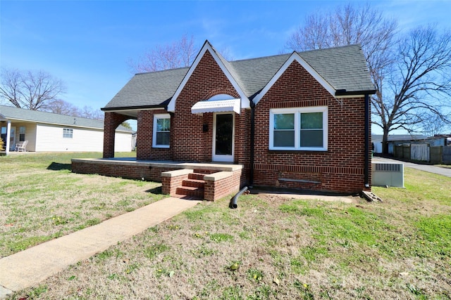 bungalow-style house featuring brick siding, roof with shingles, and a front yard