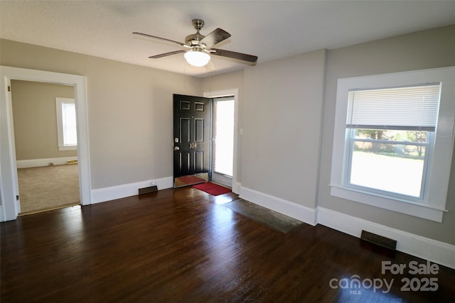 foyer entrance with visible vents, dark wood finished floors, a wealth of natural light, and baseboards