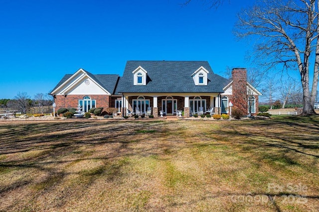 view of front of property with a porch, a chimney, and a front yard