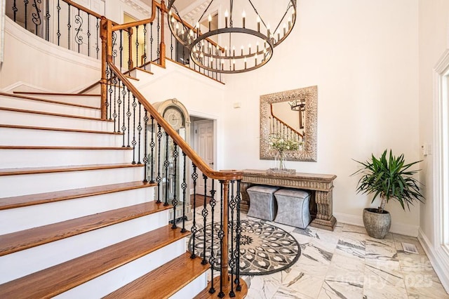 staircase featuring marble finish floor, a towering ceiling, and baseboards