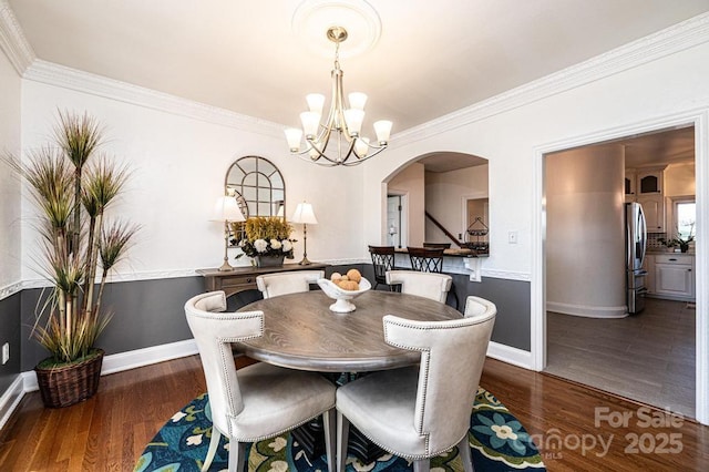 dining room with arched walkways, crown molding, dark wood-style flooring, and baseboards