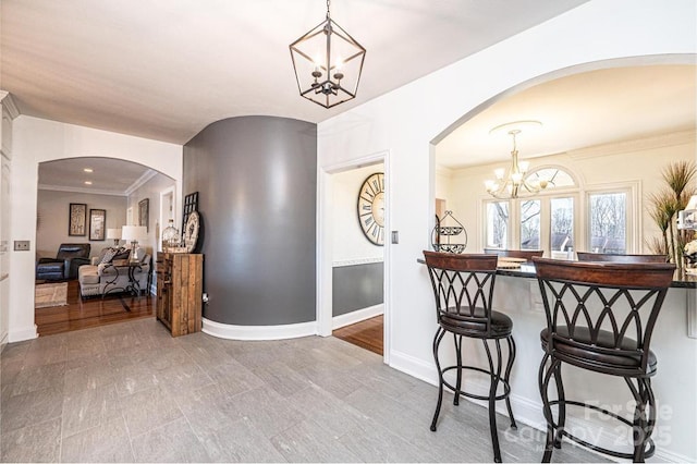 hallway with baseboards, arched walkways, and an inviting chandelier